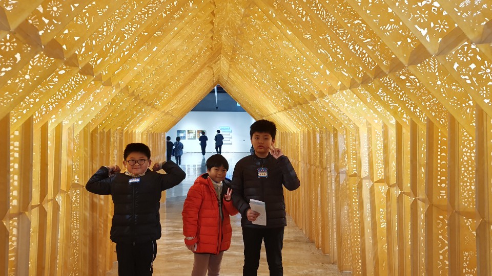 전시된 종이 터널 안에서 사진을 찍는 아이들