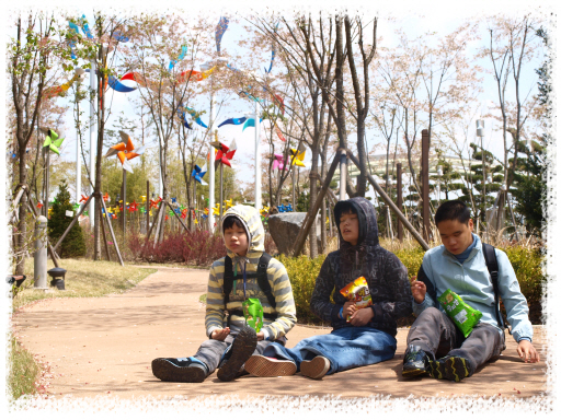 김현지, 강현정, 박도언 학생이 길가에 앉아 휴식을 취하고 있는 장면입니다.