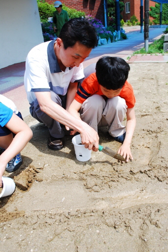 담임선생님이 채현이와 함께 흙을 정성껏 화분에 넣고 있다. 