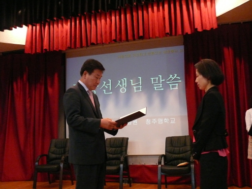 교장선생님께서 김순옥선생님께 교육감 표창을 전달하는 장면입니다.