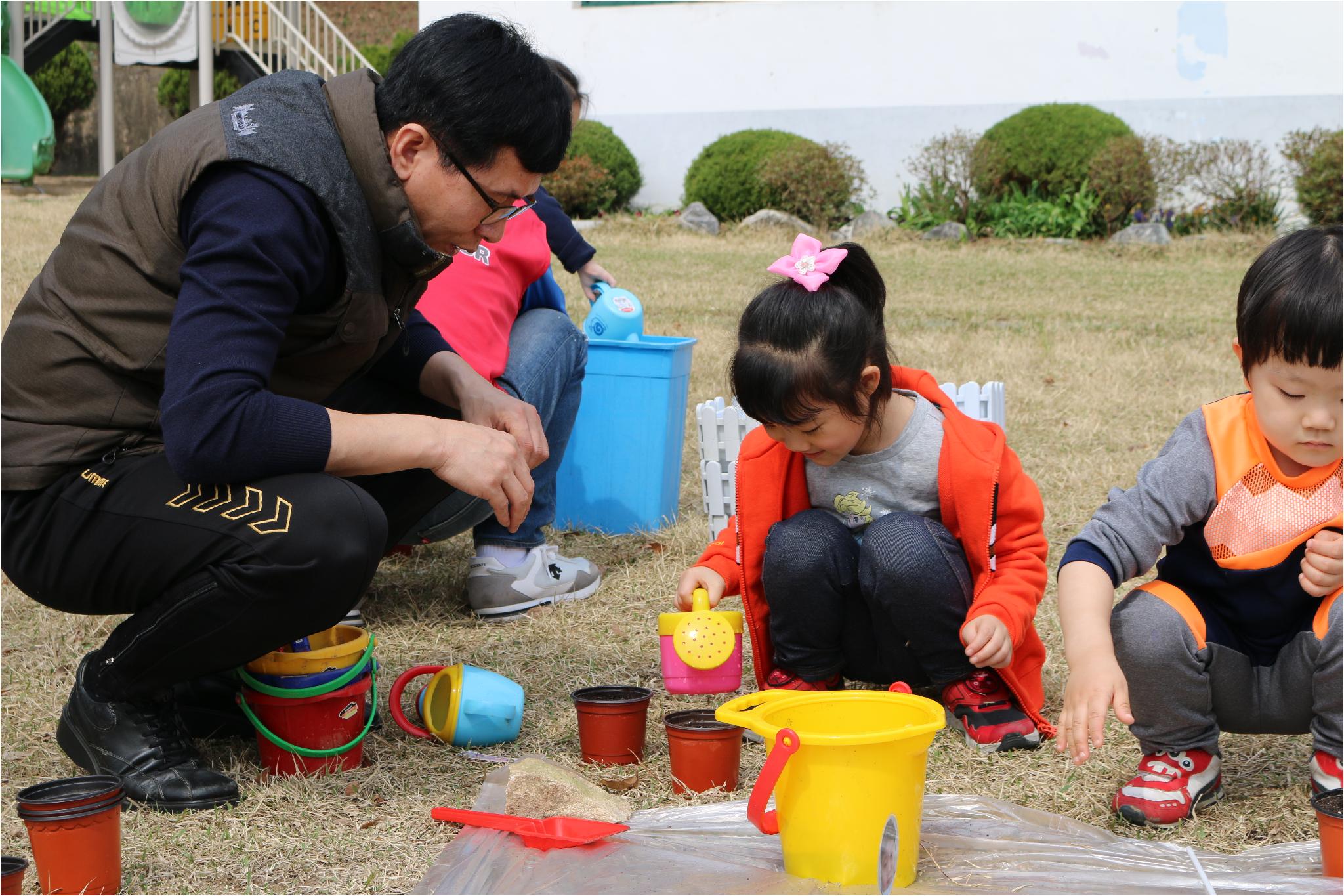 선생님의 도움을 받아 씨앗을 심고 있는 아이.