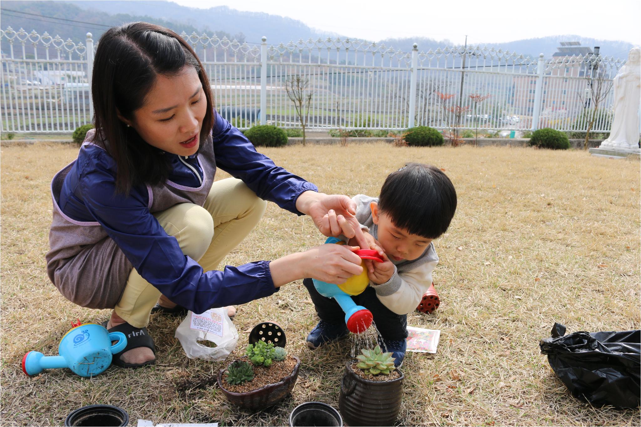 화분에 물을 주고 있는 아이.