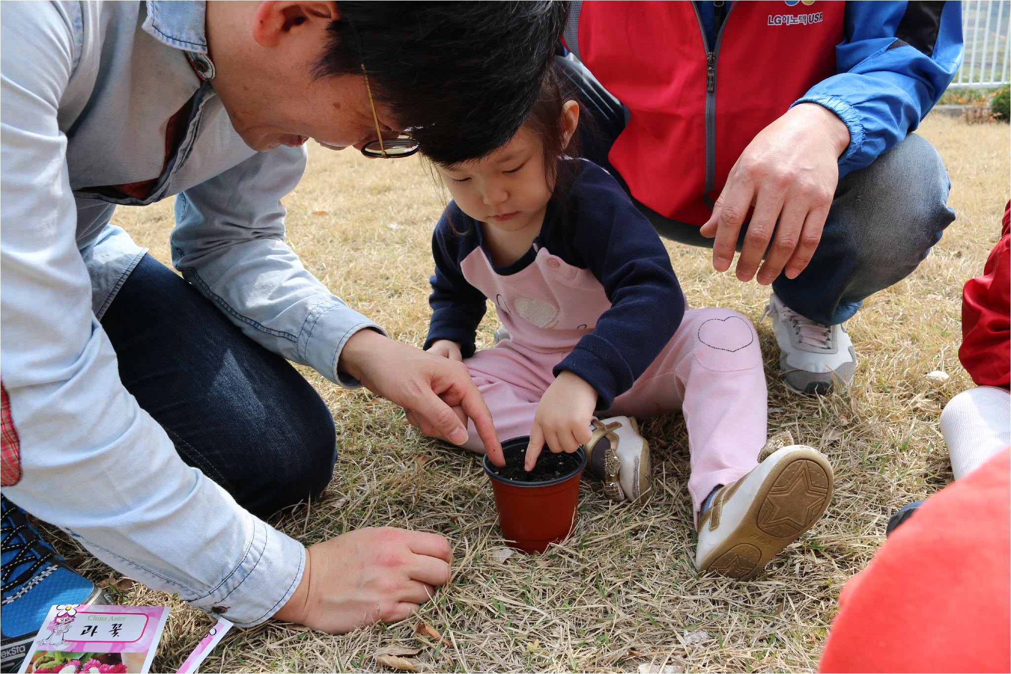 선생님의 도움을 받아 씨앗을 심고 있는 아이.