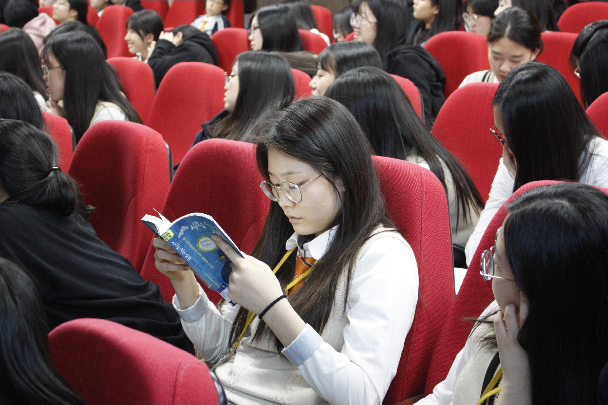 산남 여신이 책을 보며, 작가의 말을 듣고 있다.