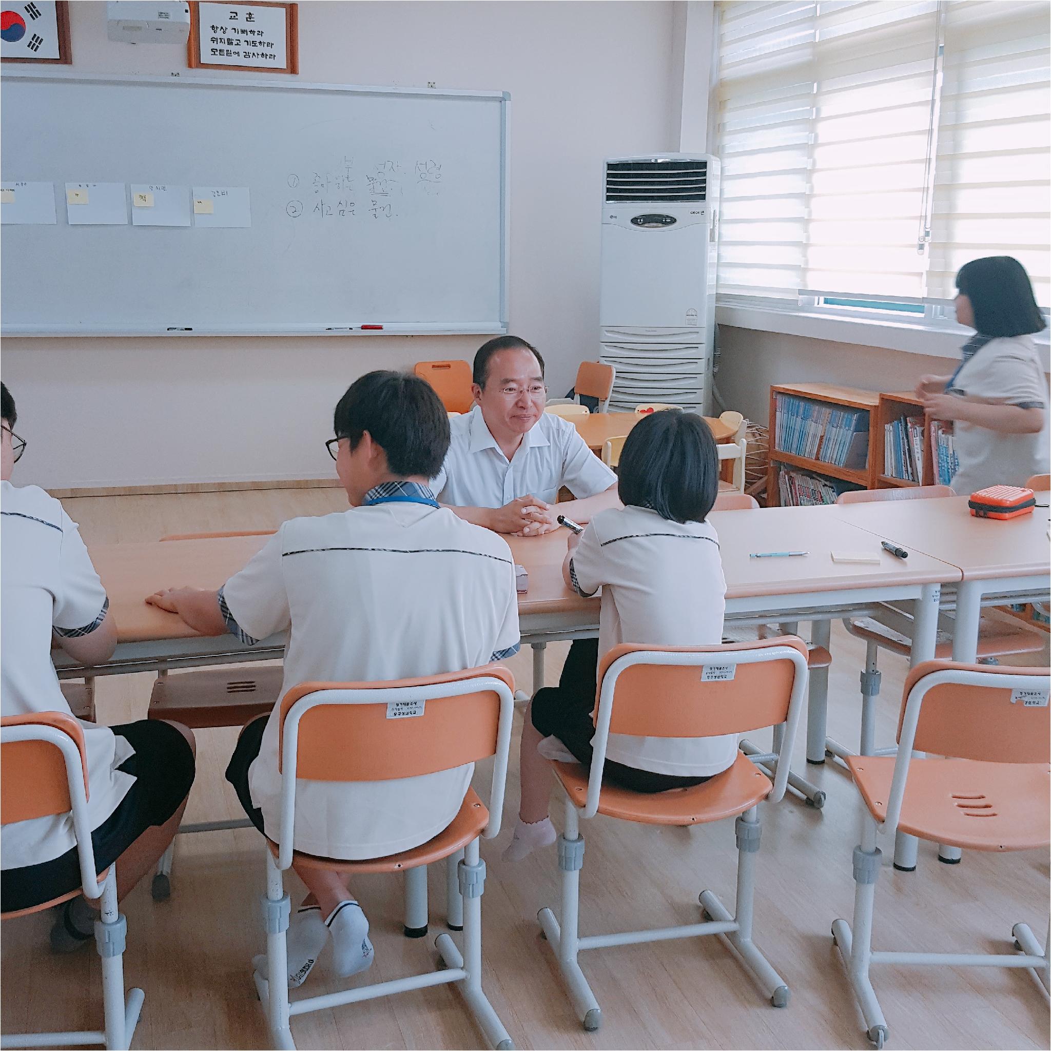 선생님과 학생들이 마주앉아 이야기를 나누고 있습니다.