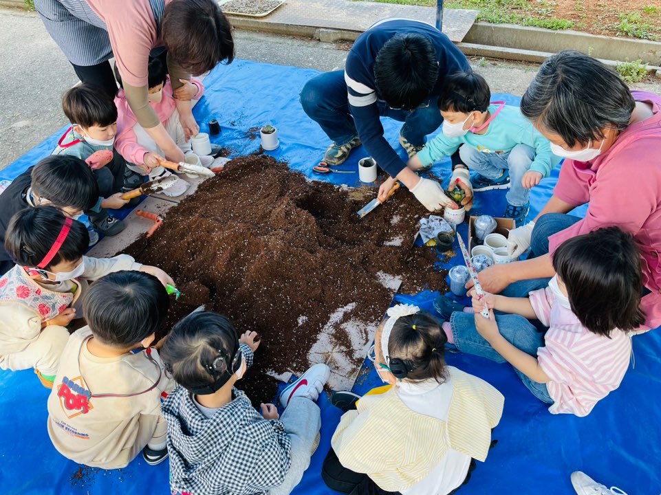 선생님이 흙을 화분에 담으며 다육이를 심고 있어요