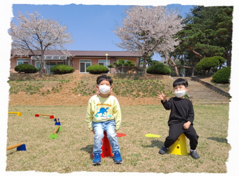 두명의 아동이 봄꽃 앞에서 사진을 찍고 있어요.