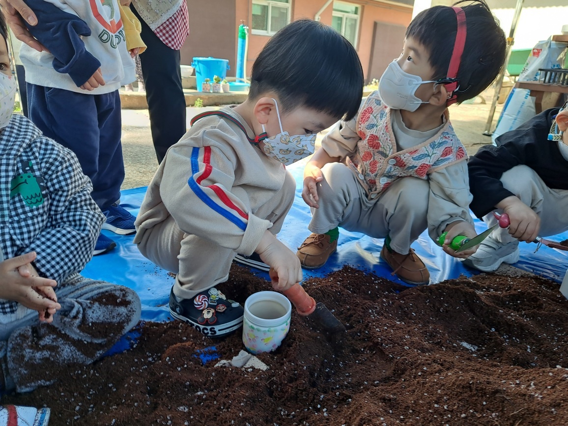 유치원 아이들이 흙을 화분에 담고 있어요